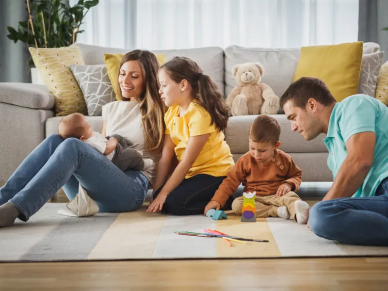 Parents and three children playing together in a living room