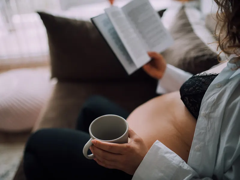 Pregnant woman relaxing on a sofa with a warm drink