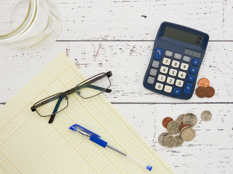 Calculator with coins and glasses on a desk