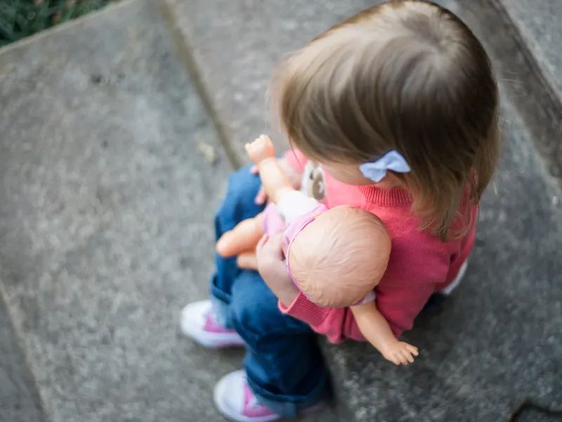 Toddler sitting on the floor cuddling a doll