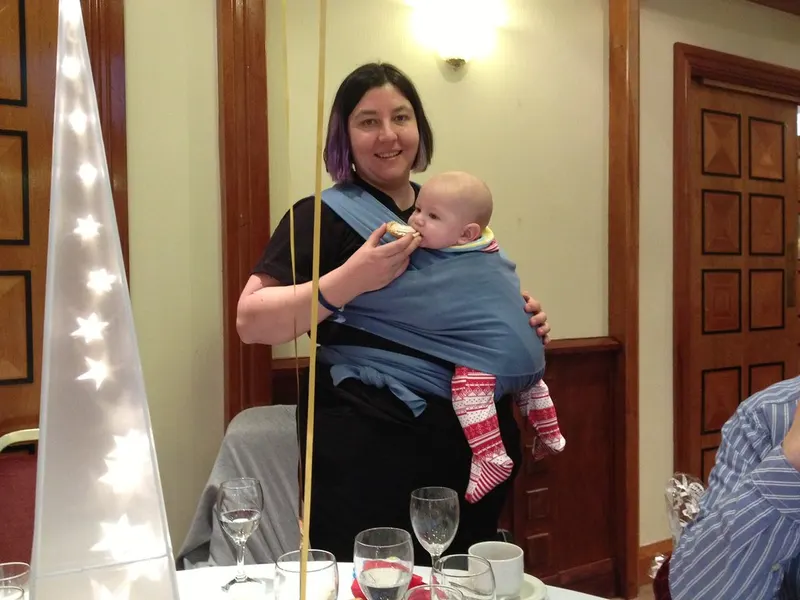 Mother holding a baby at the table during a meal