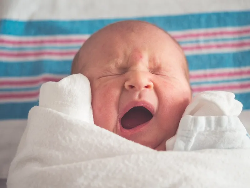 Newborn baby wrapped snugly in a soft striped blanket