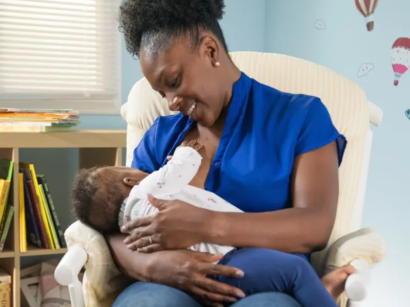 Mother breastfeeding her baby in a chair