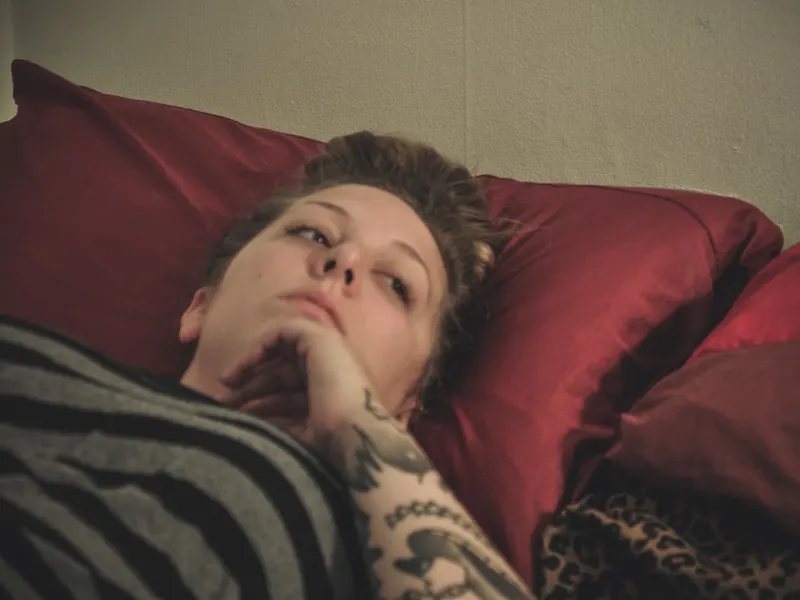 Tired woman resting on a sofa under a blanket