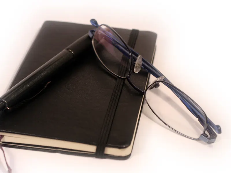 Diary, pen and reading glasses on a desk