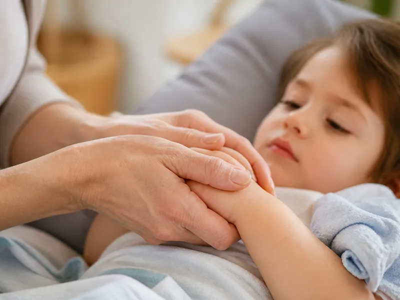 Parent holding a child’s hands with a cool flannel nearby