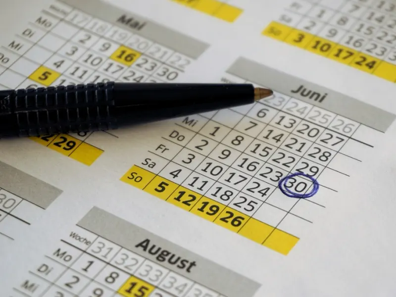 Pen circling dates on a paper calendar
