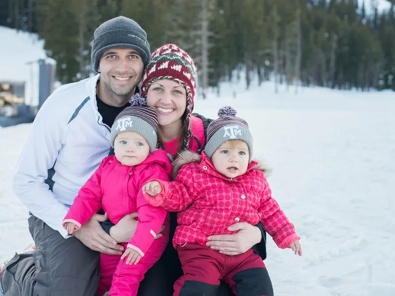 Parents holding twin babies in the snow