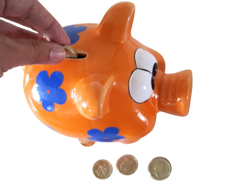 Child putting coins into a piggy bank