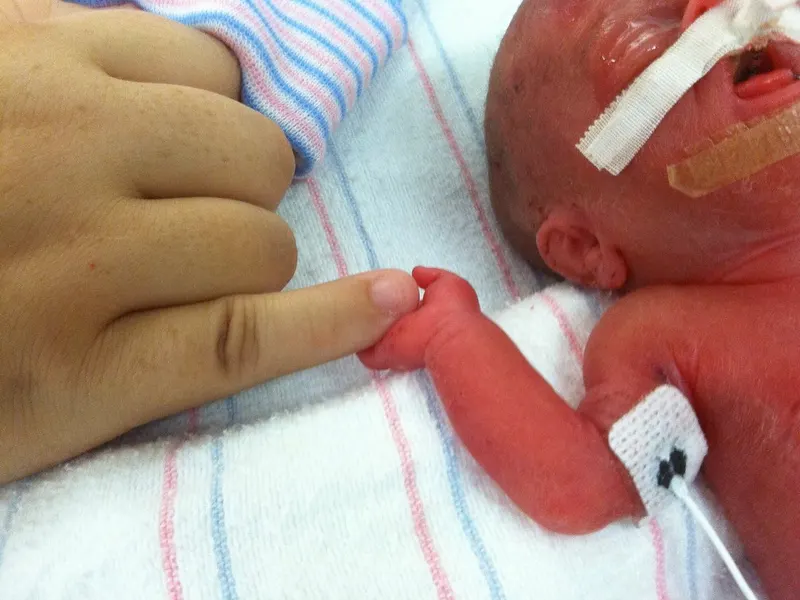 Premature baby in NICU gripping a parent’s finger