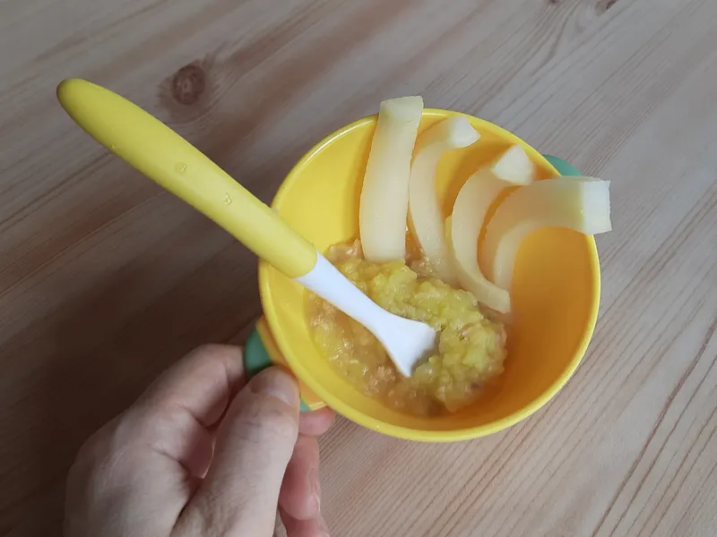 Bowl of orange vegetable purée with a baby spoon