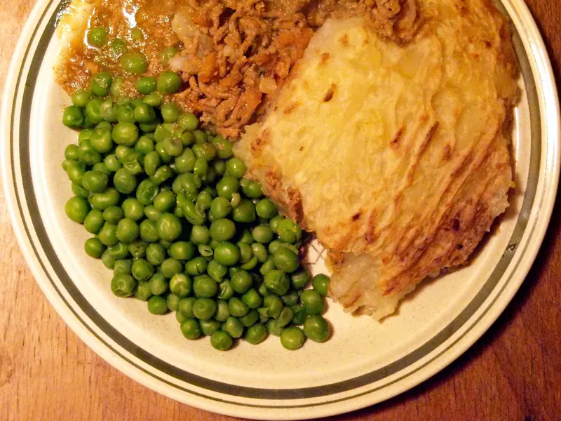 Mashed-potato-topped pie served with peas