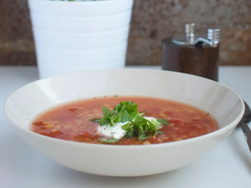 Bowl of red lentil soup with a herb garnish