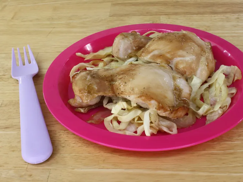 Roasted chicken thighs served on a plate with cabbage