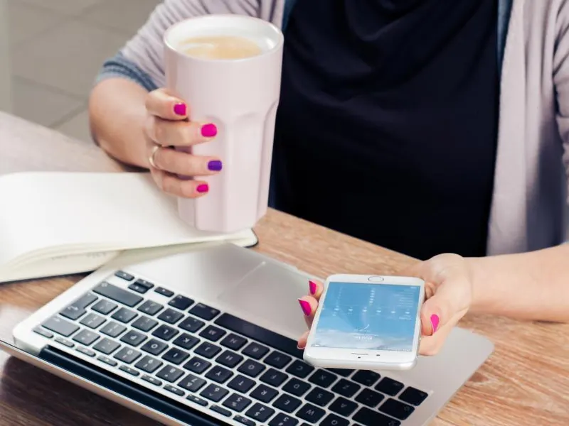 Woman working at a laptop with a coffee in hand