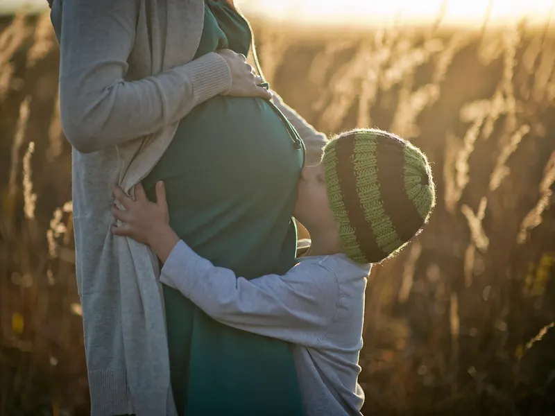 Toddler hugging their pregnant mother’s bump