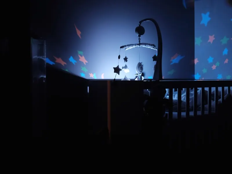 Cot mobile turning above a darkened nursery cot