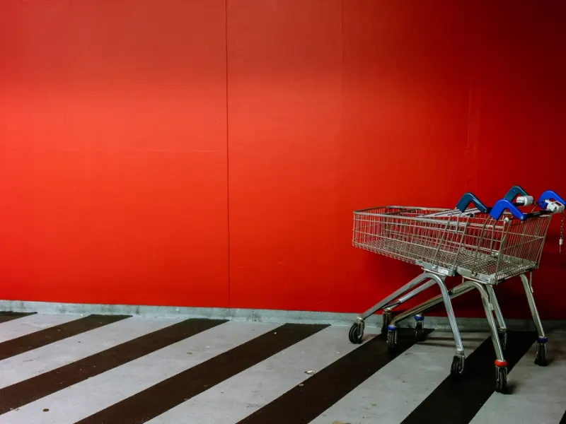 Shopping trolley against a bold red supermarket wall