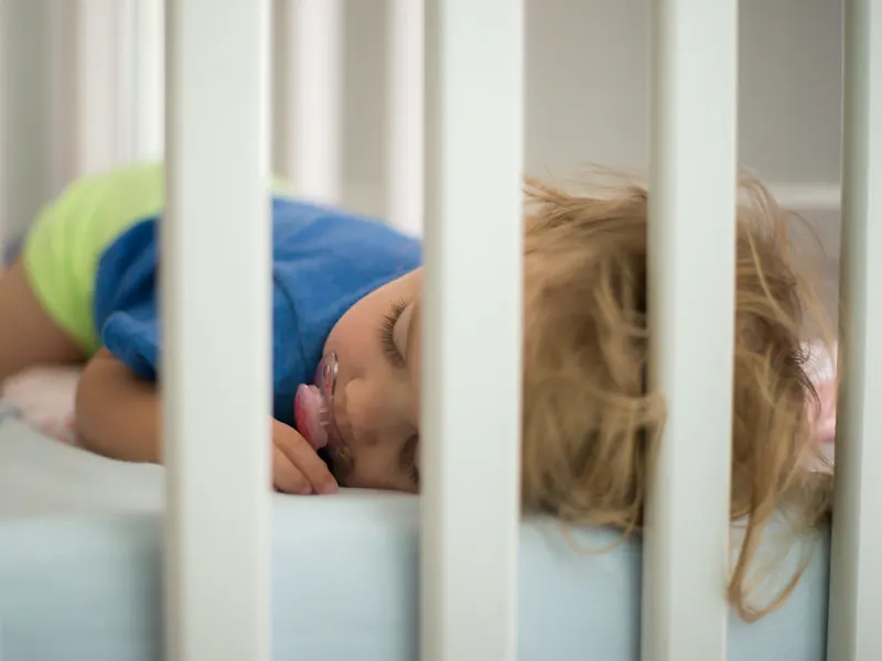 Toddler asleep in a cot