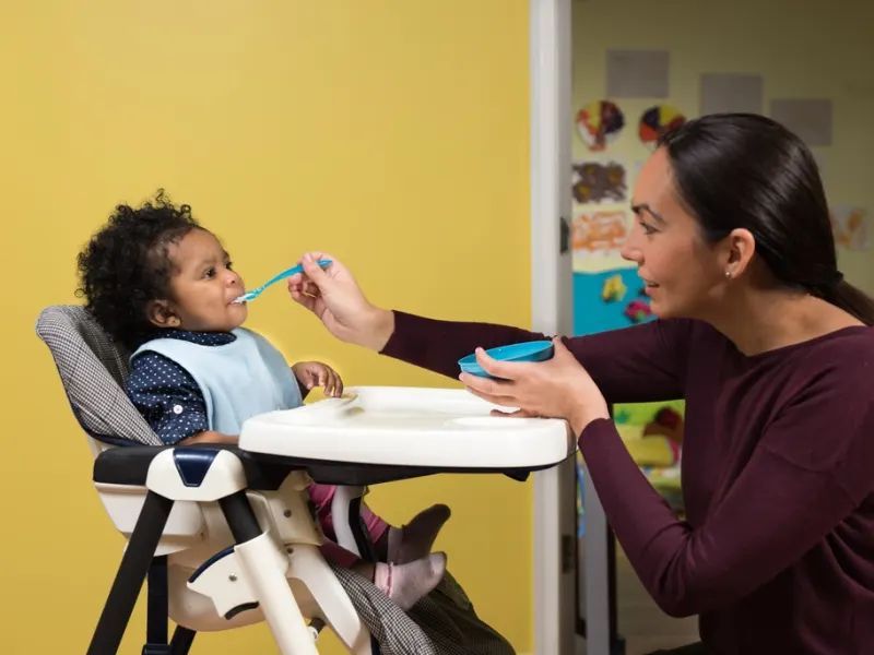 Baby in a highchair being fed with a spoon